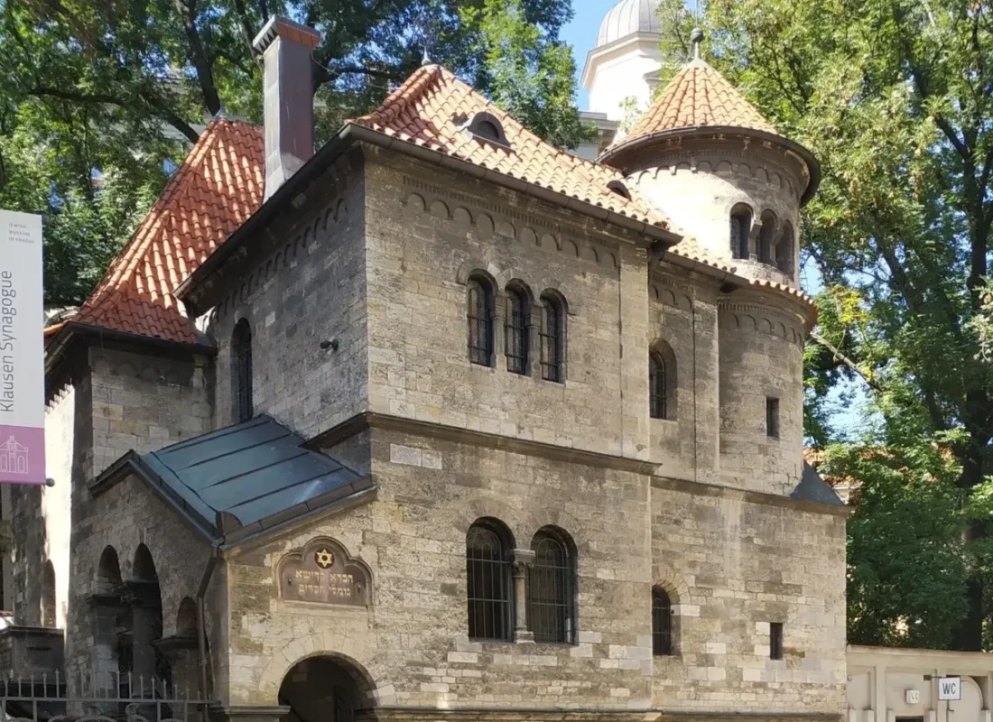 старинное здание из серого камня с черепичной крышей и круглой башней в еврейском квартале Праги