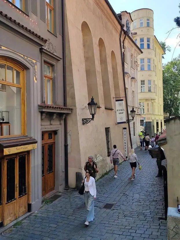вид на стену высокой синагоги с вывеской Judaica Shop на фоне исторической застройки пражского еврейского гетто