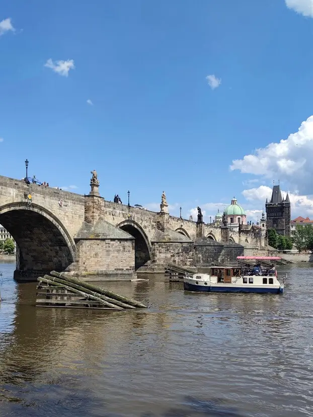 Карлов мост в Праге: вид на исторические арки, скульптуры, Староместскую мостовую башню и экскурсионный теплоход на реке Влтаве
