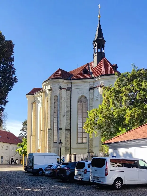 готический костел Святого Роха в Страговском монастыре за припаркованными автомобилями