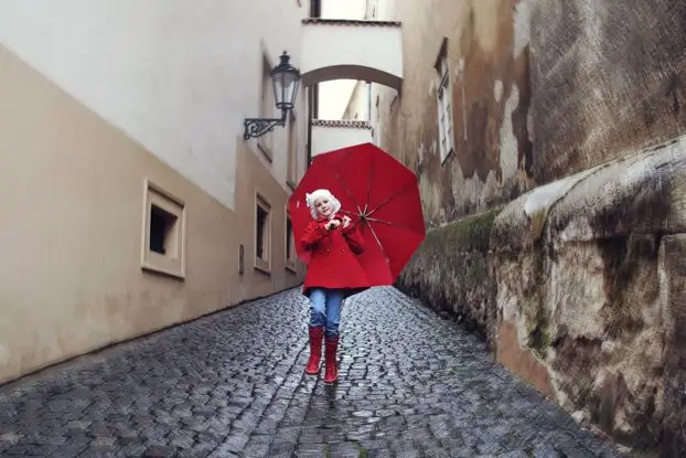 фотосессии в Праге – детская и семейная съемка на старинных улочках девочка в красном пальто с большим красным зонтом на мощеной улочке – фотосессии в Праге