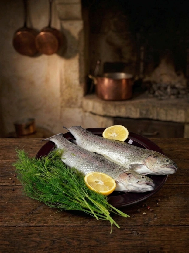 Чешская кухня. Форель в сливочном соусе свежая речная форель с дольками лимона и пучком укропа на темном блюде